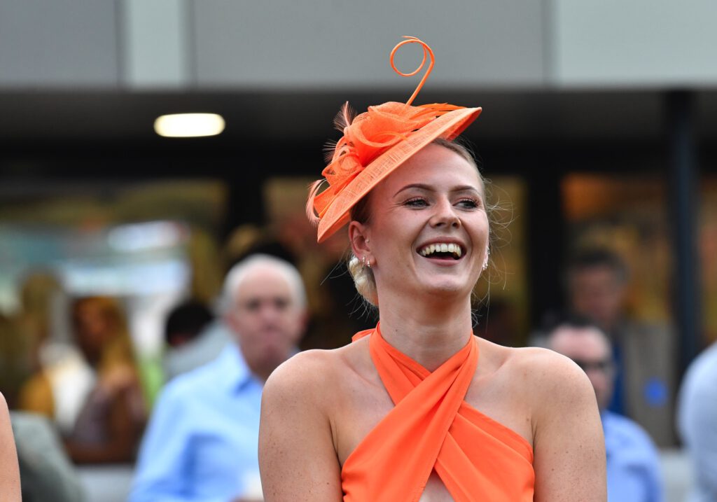 lady giggling in a fancy hat at ladies day